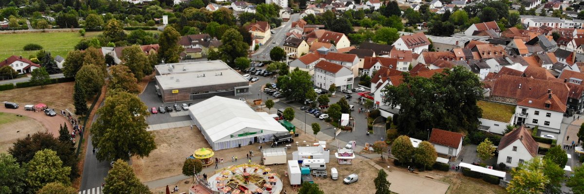 Luftbild, Ausschnitt einer Kleinstadt, davor Festplatz mit Festzelt, Karussell und Buden