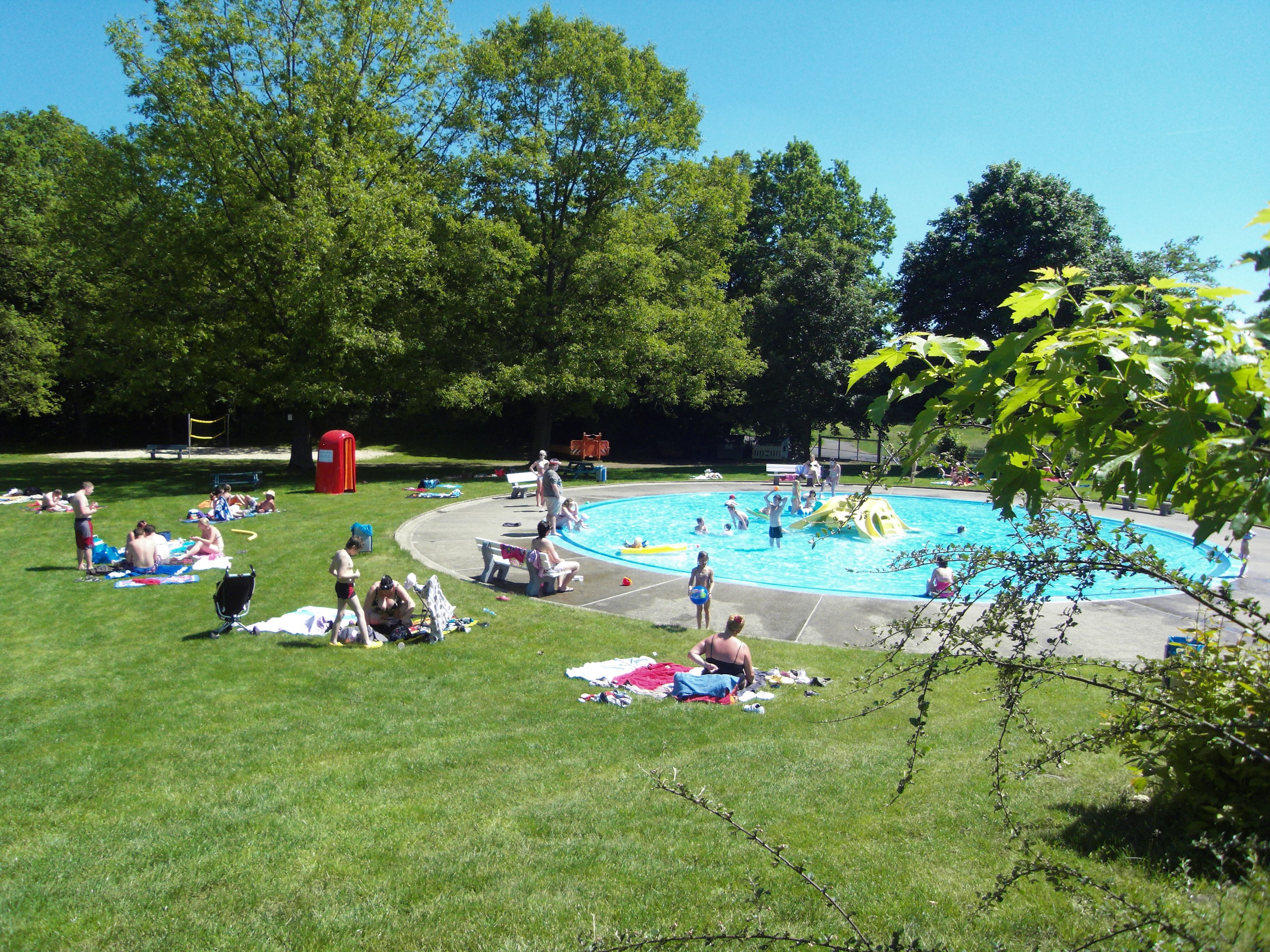 Planschbecken im Freibad mit Menschen im Gras